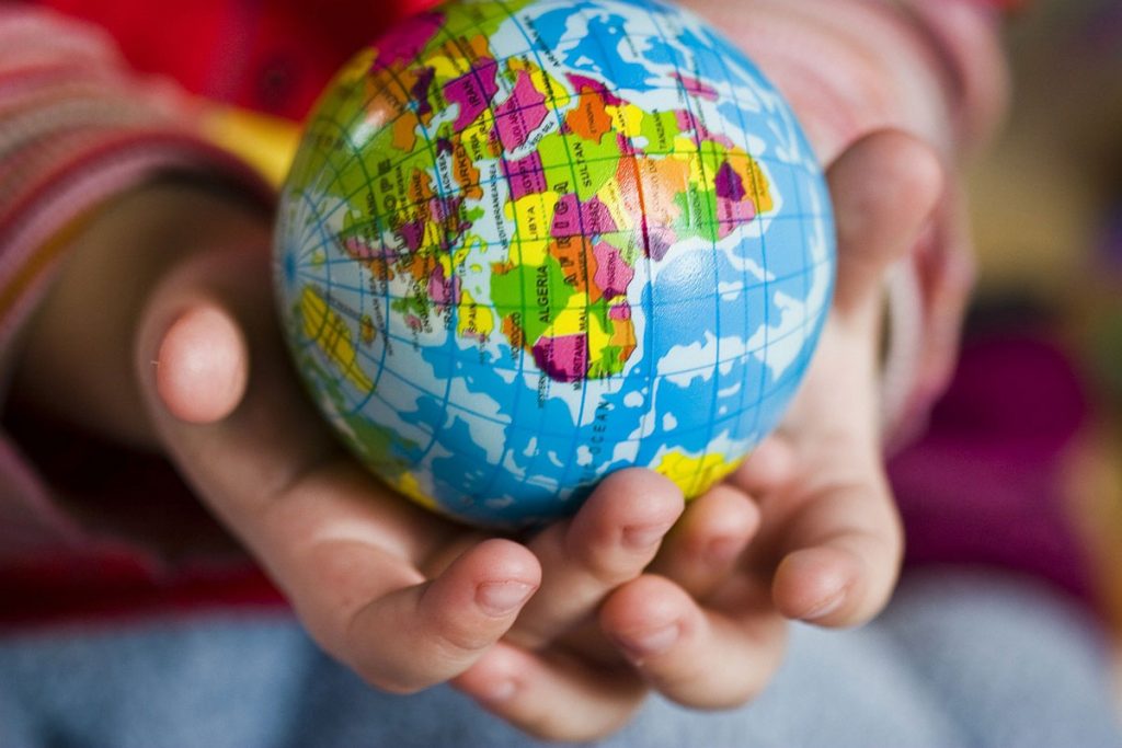 deux mains d'enfants portent un globe terrestre miniature