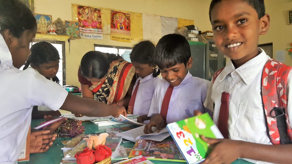 Dans une plantation de thé au ri lanka, des enfants en tenue d'écolier, feuillettent sourire aux lèvres des livres posés sur une table.