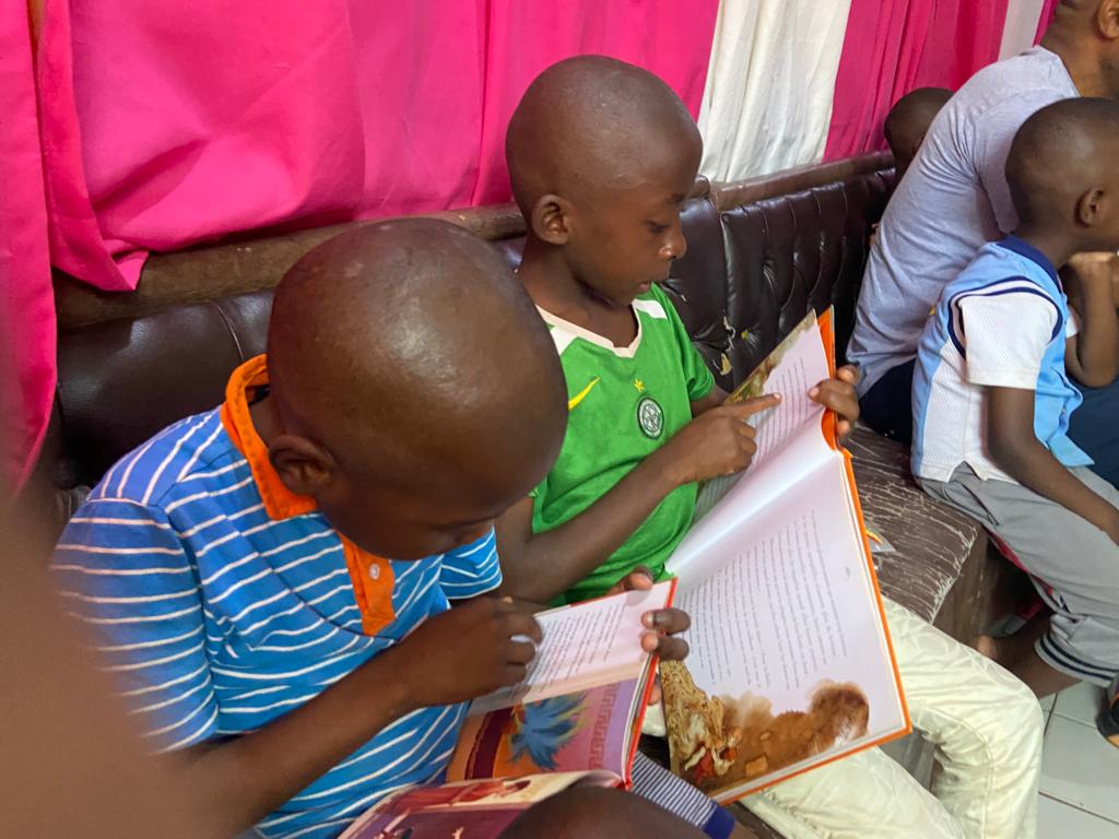 Deux jeunes garçons des orphelinats visités, sont assis, en train de lire un livre. L'un porte un haut bleu tandis que l'autre porte un tee-shirt vert.