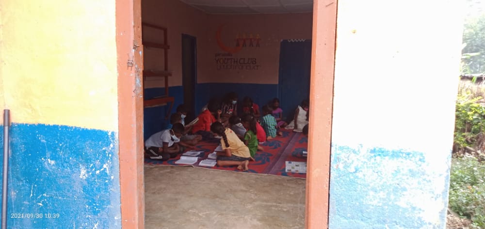 Une pièce relativement sombre dans laquelle une douzaine d'enfants agenouillés sur des tapis lisent des livres. Cela se passe dans un village de plantation de thé au Sri Lanka 